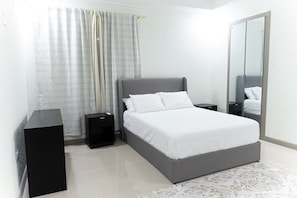 A modern bedroom with a bed, bedside tables, a wardrobe, and a large mirror. - Spacious 2-bedroom apartment in serene Kingston with AC , pool , and gym access (Kingston)