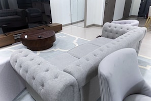 A modern living room with a grey sectional sofa, a wooden coffee table, and a glass partition. - Spacious 2-bedroom apartment in serene Kingston with AC , pool , and gym access (Kingston)