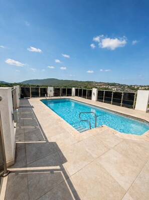 A rooftop swimming pool with a clear view of the surrounding landscape. - Spacious 2-bedroom apartment in serene Kingston with AC , pool , and gym access (Kingston)