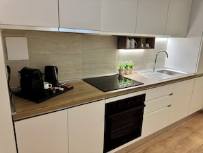 Eine moderne Küche mit einem eingebauten Geschirrspüler, einer Kaffeemaschine und einem Spülbecken.