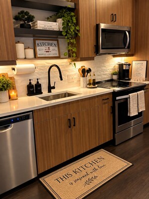 A modern kitchen with wooden cabinets, stainless steel appliances, and a built-in microwave. - Cozy 1-bed Midtown apartment ATL STAY Walkable and Central location (atlanta)