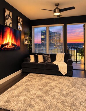 A modern living room with a black sofa, a white shag rug, and a fireplace. - Cozy 1-bed Midtown apartment ATL STAY Walkable and Central location (atlanta)