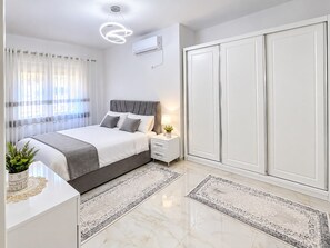 A modern bedroom with a bed, bedside table, nightstand, and wardrobe. - Airport Tirana Rooms (Tirane)