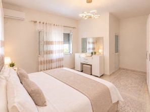 A bedroom with a bed, a bedside table with a lamp, a window with curtains, a bathroom with a mirror, and a shower area. - Airport Tirana Rooms (Tirane)