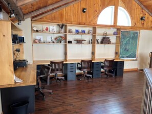 A room with wooden desks, chairs, and shelves with various items.