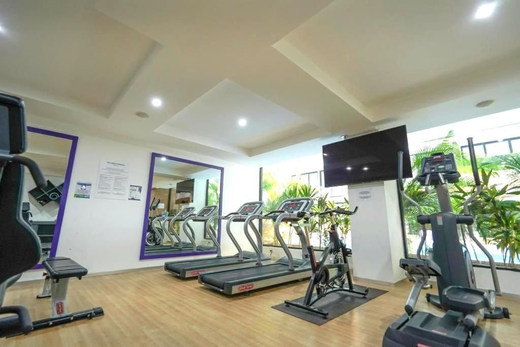 Een fitnessruimte met loopbanden, een hometrainer en een gewichtbank.