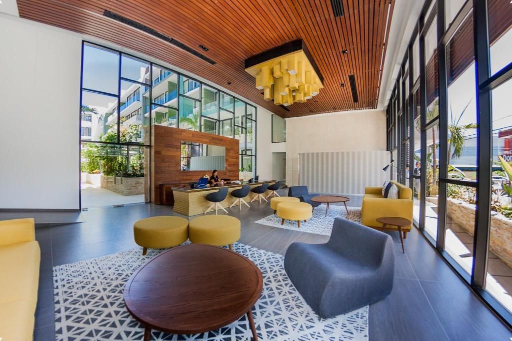 A modern lobby with a reception desk, seating area, and large windows.