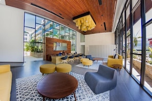 A modern lobby with a reception desk, seating area, and large windows. - The City Condos Playa del Crmen (gonzalo Guerrero)