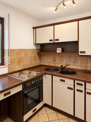 A kitchen with a stove, oven, sink, and cabinets. - Bright 1-bedroom apartment with a terrace – quiet location (Korb)