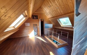 A wooden attic room with skylights, a small enclosed area with a railing, and a view of the outdoors. - Getaway in Northern Brittany: House with a garden, 1 km from the sea and with access to the GR34 trail (Plougasnou)