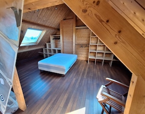A small, wooden room with a sloped ceiling, a bed, built-in shelves, and a skylight. - Getaway in Northern Brittany: House with a garden, 1 km from the sea and with access to the GR34 trail (Plougasnou)