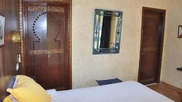 A room with a wooden door, a mirror, and a bed with pillows.