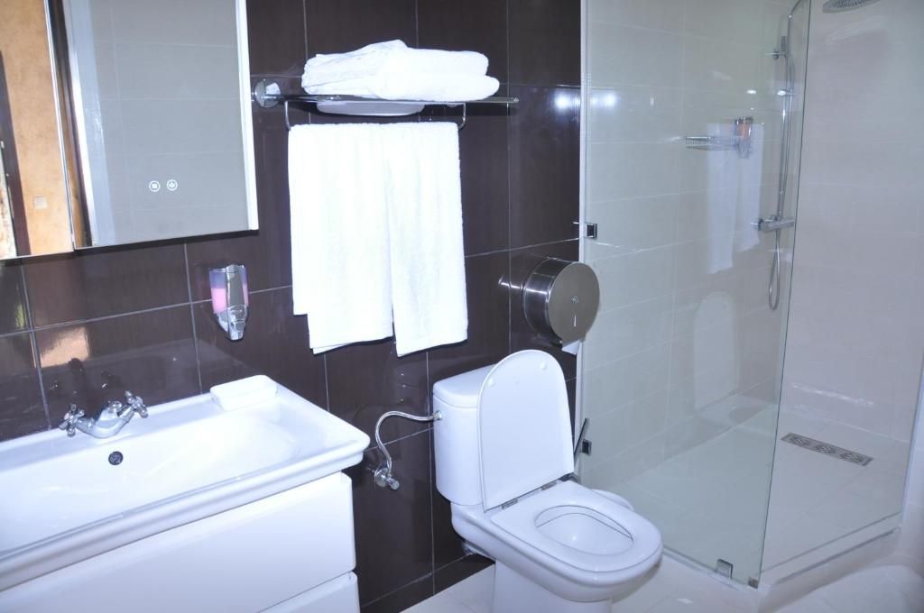 A modern bathroom with a white sink, toilet, and glass-enclosed shower.