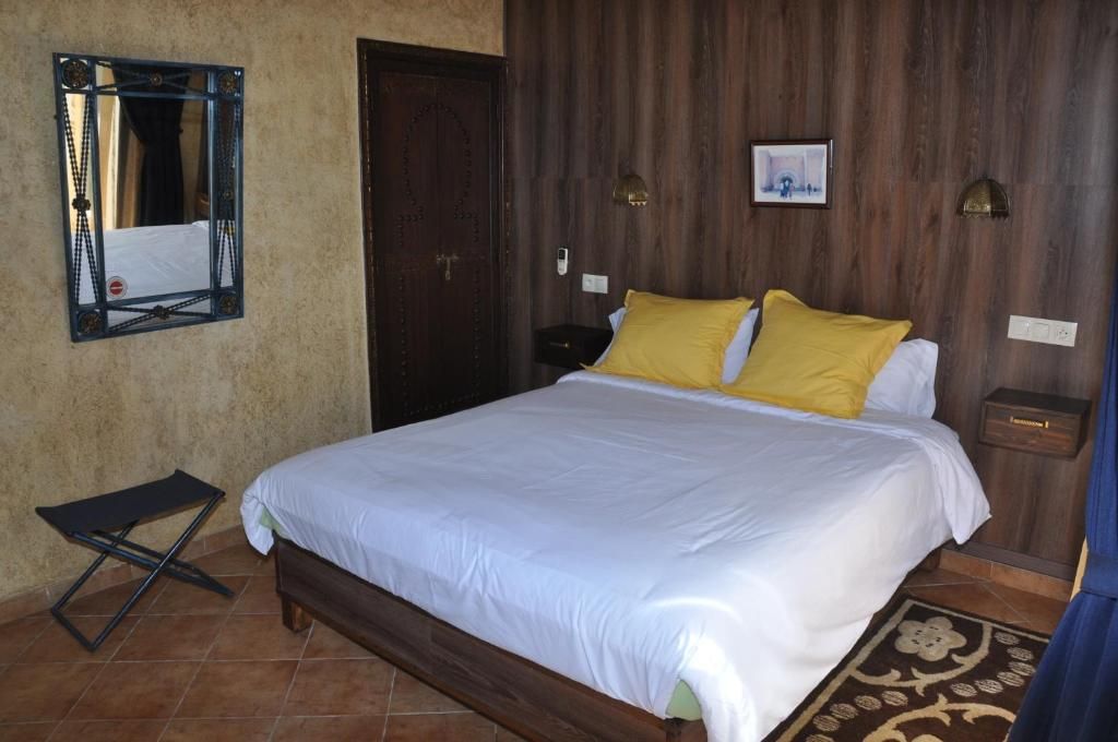 A bedroom with a bed, a nightstand, a mirror, and a door.