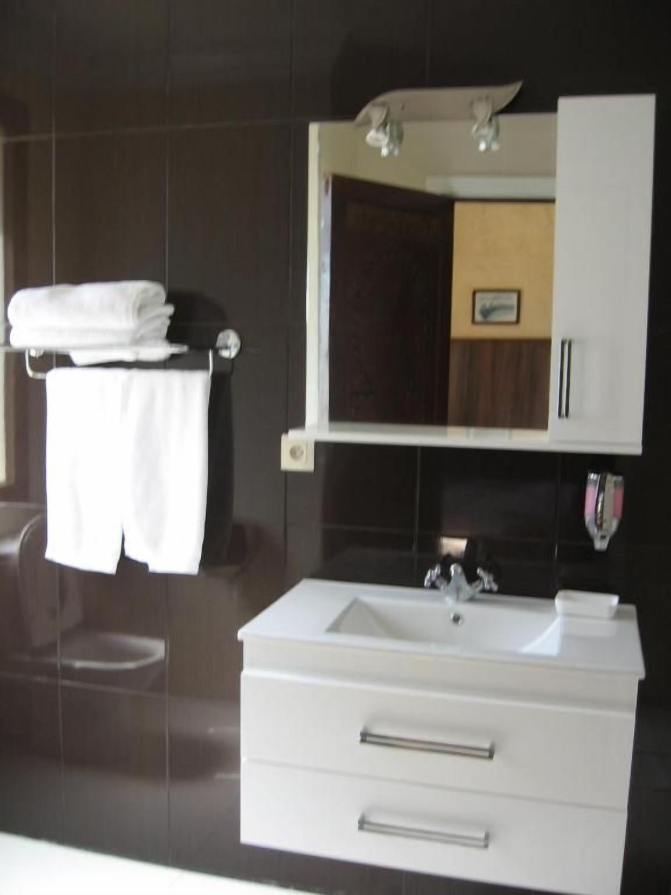 Un baño moderno con un tocador blanco, un espejo encima y un perchero con toallas dobladas.