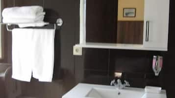 Un baño moderno con un tocador blanco, un espejo encima y un perchero con toallas dobladas.