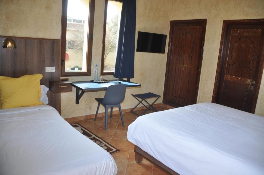 A room with two beds, a desk, a chair, and a television.