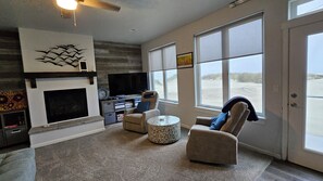 Ein Wohnzimmer mit Kamin, Fernseher und Blick auf den Strand.