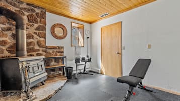 A room with a stone wall, a wooden ceiling, a black exercise chair, a door, and a mirror.