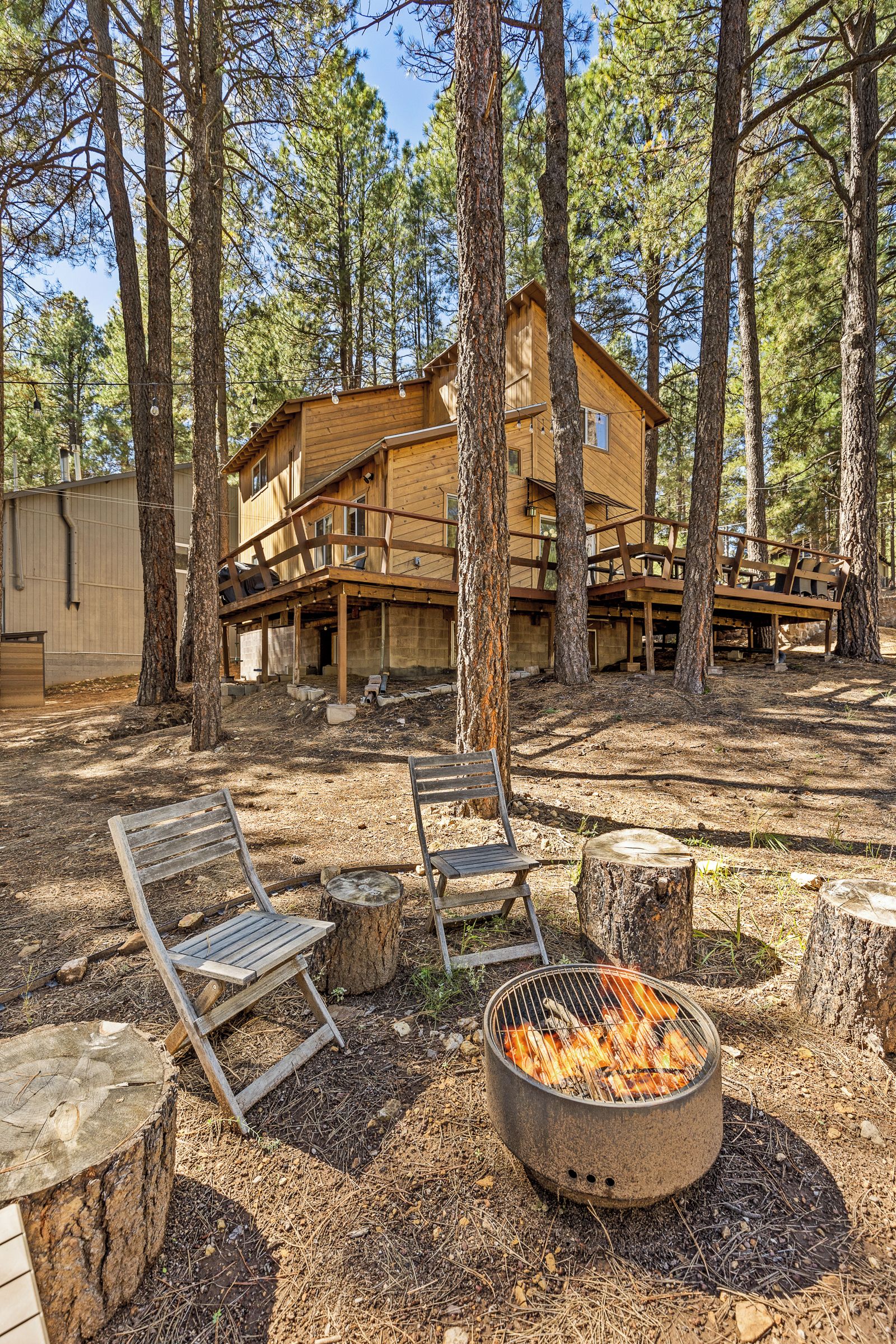 A wooden cabin with a deck, surrounded by trees.
