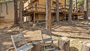 A wooden cabin with a deck, surrounded by trees.