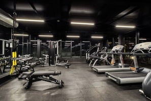 Un gimnasio con cintas de correr, mancuernas y máquinas de pesas.