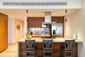 Una cocina moderna con encimeras de granito, electrodomésticos de acero inoxidable y armarios de madera.