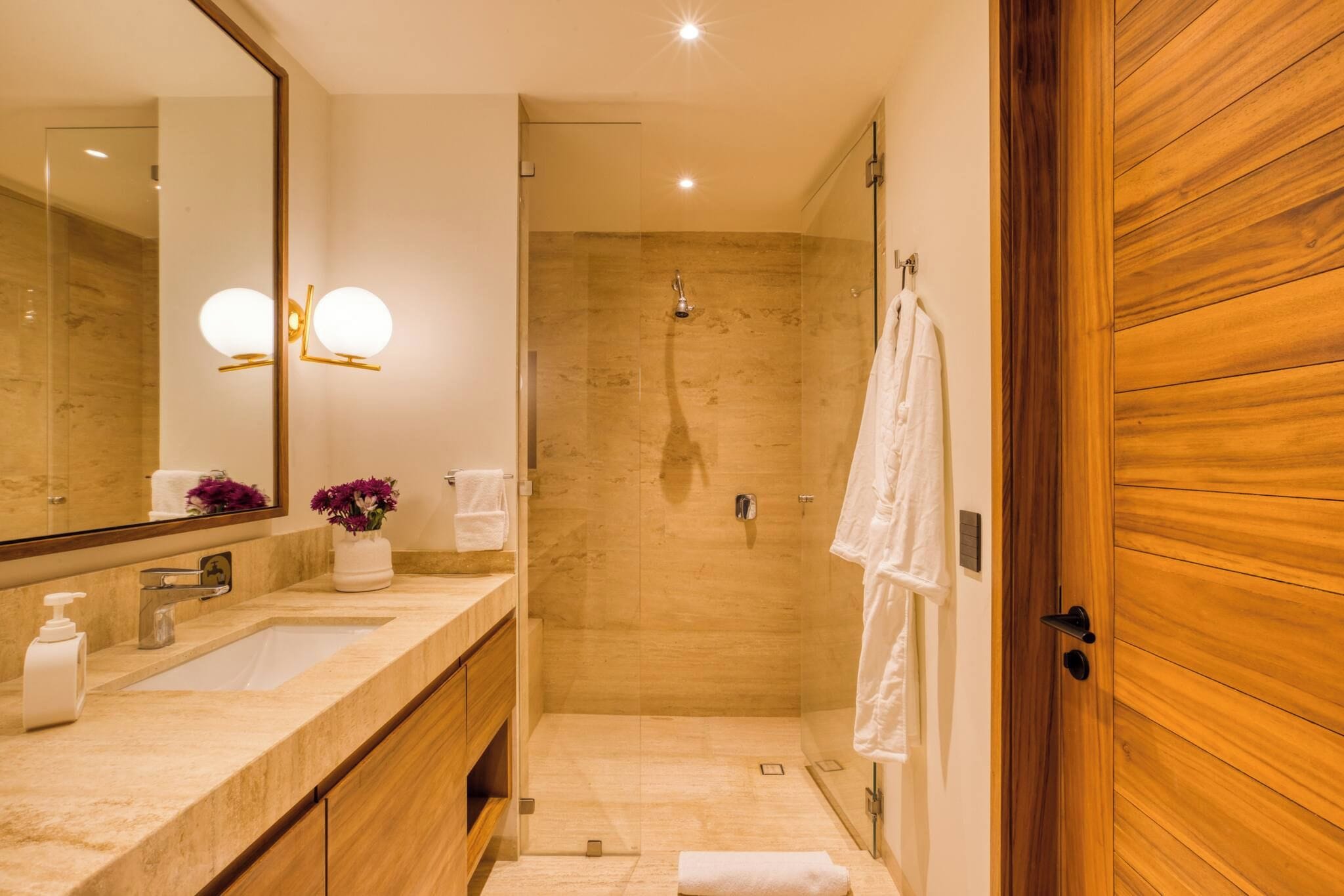 Un bany modern amb un mirall gran, un lavabo, una dutxa i panells de fusta.