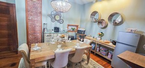 A dining area with a wooden table set for four, a kitchen area with appliances, and decorative wall mirrors. - Historic Bed & Breakfast 8 Bedrooms, Groups/family (Eureka Springs)