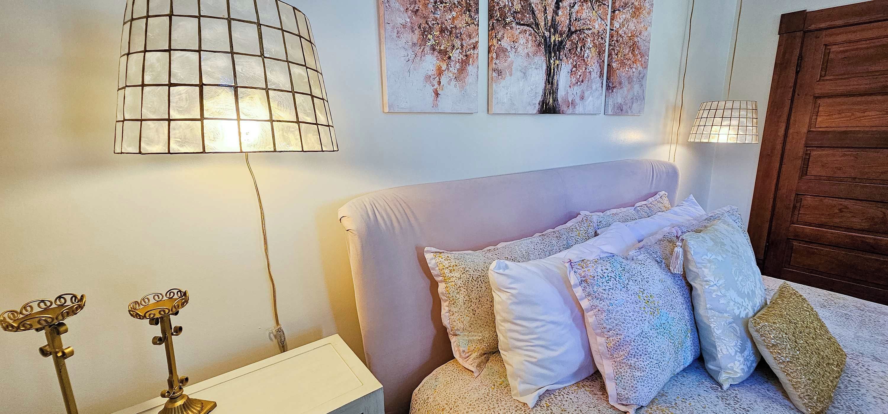 A bedroom with a bed, a lamp, and two wall-mounted paintings.