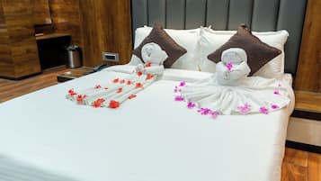 A hotel room with a neatly made bed, a wooden headboard, and a small bedside table with a lamp.