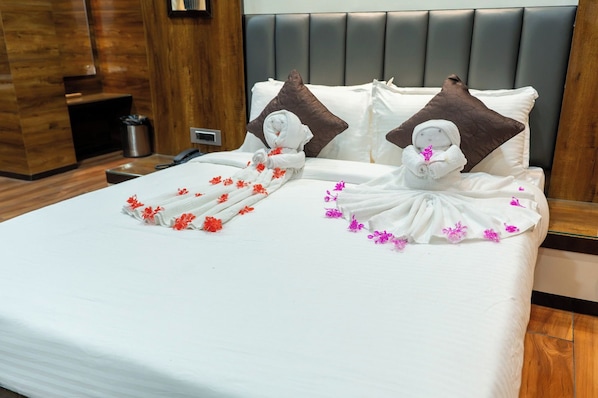Habitación de hotel con una cama bien hecha, un cabecero de madera y una mesita de noche con una lámpara.