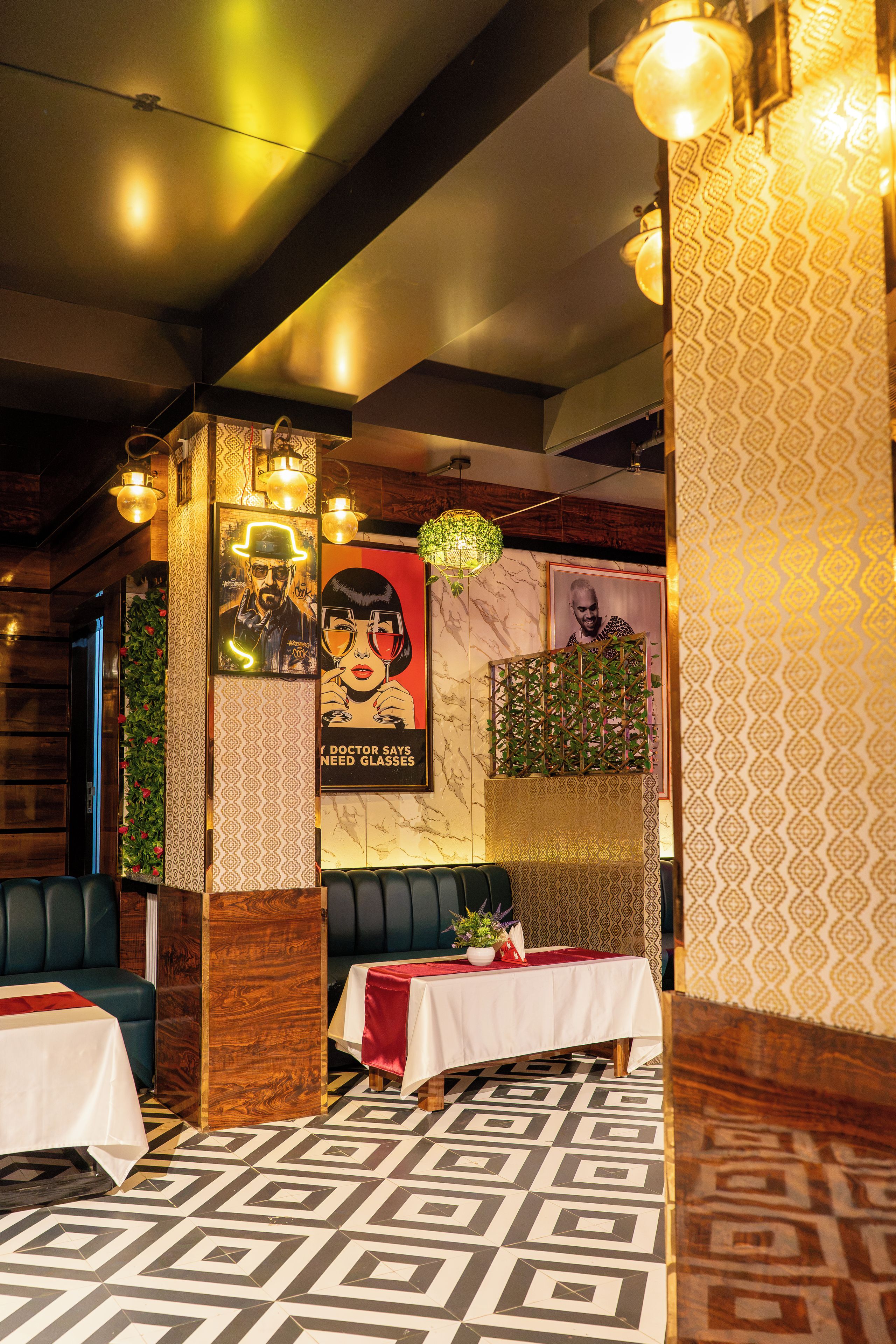 A restaurant interior with booths, patterned flooring, and wall decorations including posters and a plant.