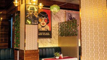 A restaurant interior with booths, patterned flooring, and wall decorations including posters and a plant.