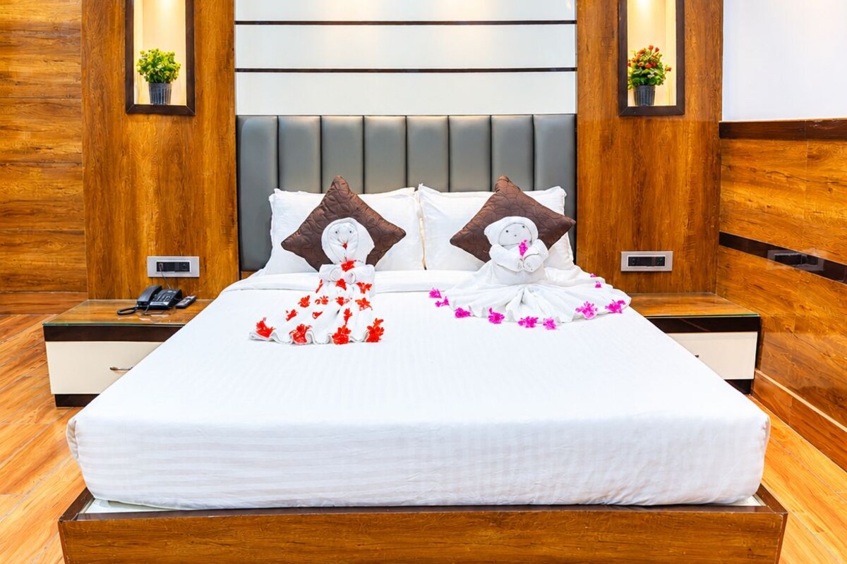 A hotel room with a large bed, wooden headboard, bedside tables with lamps, and a modern design.