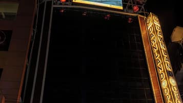 A hotel facade with a marquee sign, multiple flags, and a large illuminated sign advertising the hotel.