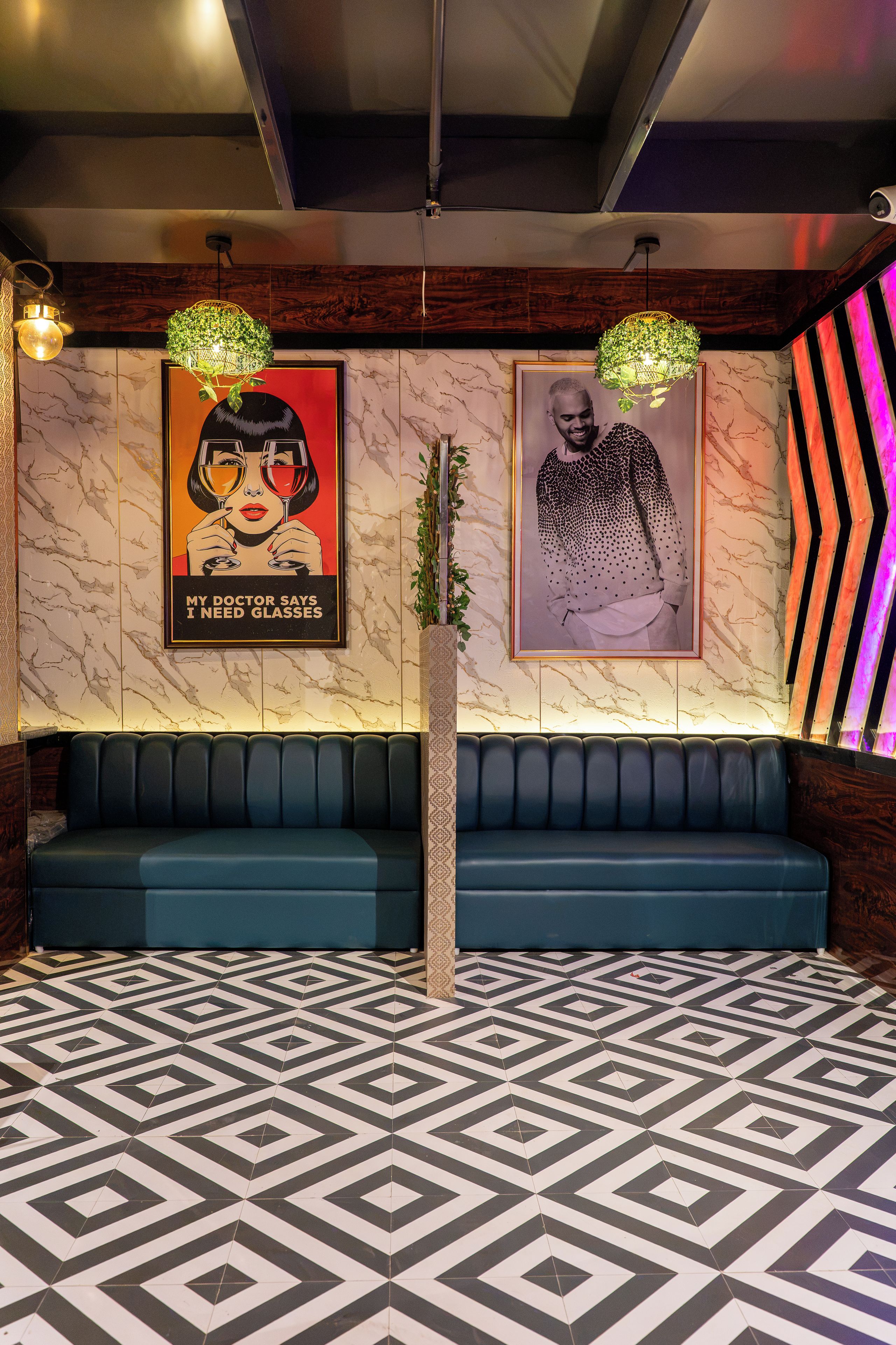 A modern interior with a patterned floor, a dark blue sofa, and two wall-mounted posters.
