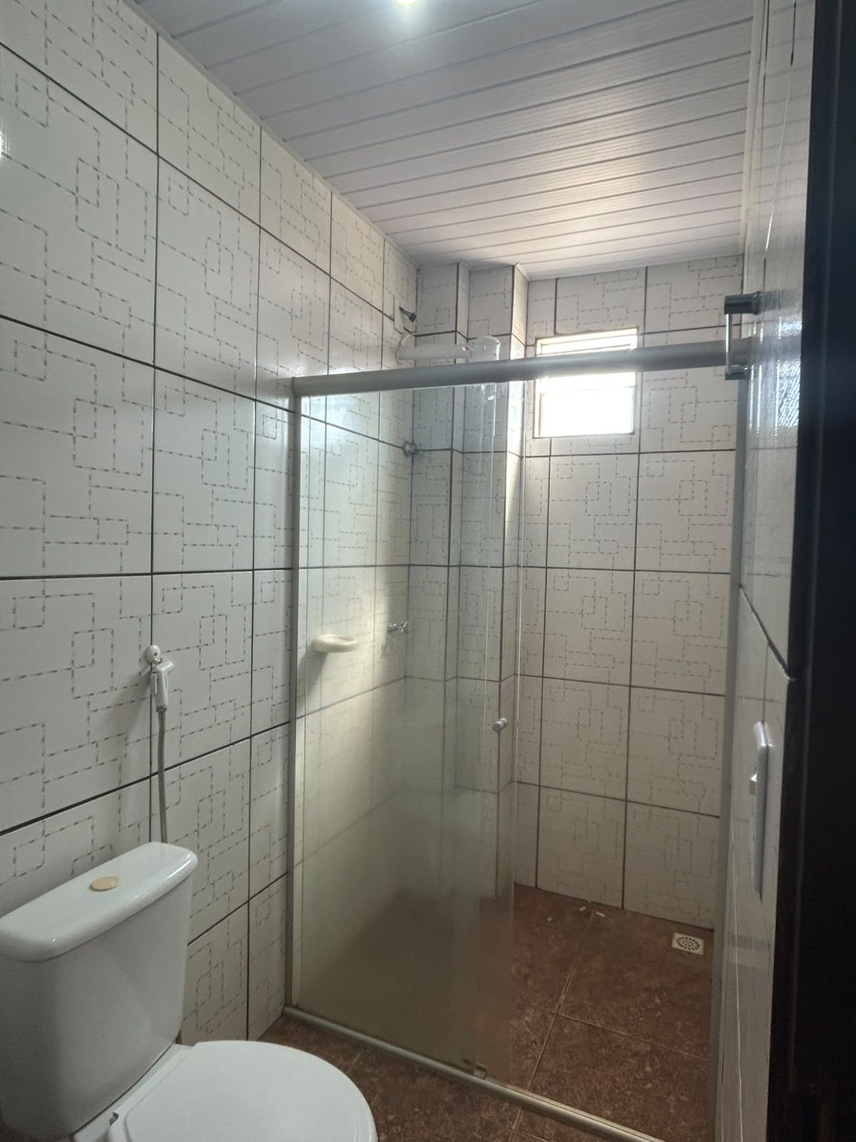 Ein Badezimmer mit Duschkabine, Toilette und gefliesten Wänden.