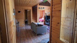 A wooden cabin interior with a sofa, a television, and a staircase leading to another room. - Orrenkolo Cabin, in Luosto, Finnish Lapland (Luosto)