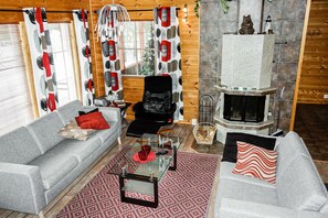 Una sala de estar acogedora con chimenea, dos sofás, una mesita de centro y una alfombra estampada.