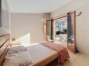 A bedroom with a bed, a bedside table, and a window. - Authentic farmhouse, pool, garden, near the beaches (Villelongue-de-la-Salanque)