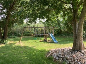 A playground with a slide and swings, surrounded by trees and grass. - Authentic farmhouse, pool, garden, near the beaches (Villelongue-de-la-Salanque)