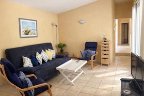 Ein Wohnzimmer mit einer Couch, zwei Sesseln, einem Couchtisch und einem Fernseher.