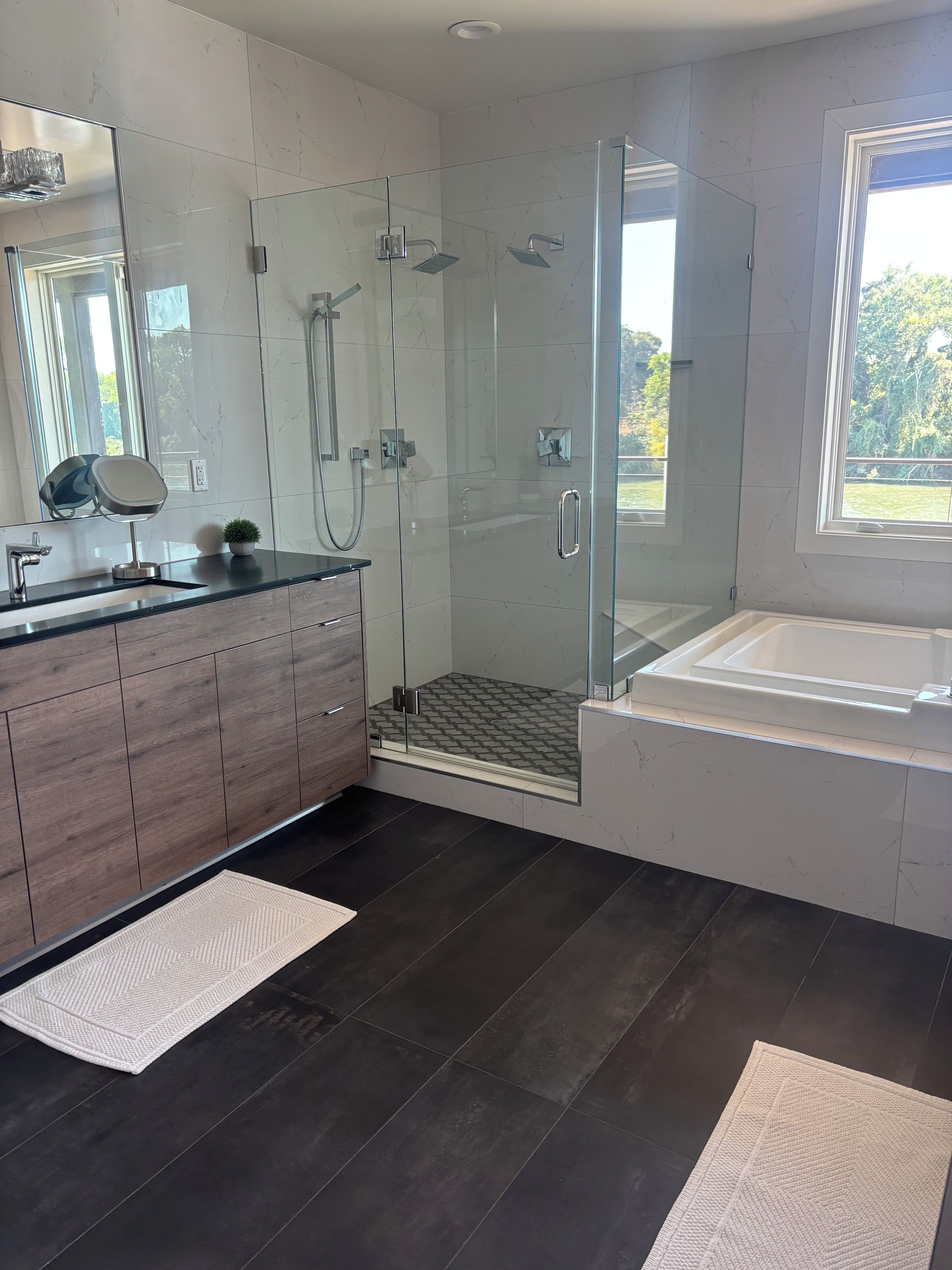 Une salle de bain moderne avec une douche à parois de verre, un grand miroir et une baignoire.