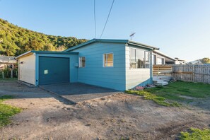 A single-story house with a garage, a small porch, and a fenced backyard. - The Little Jetty - Motuoapa Holiday Home (Motuoapa)