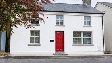A two-story building with a red door, white walls, and multiple windows.