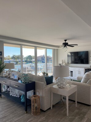 A modern living room with a large TV, comfortable seating, and a view of the outdoors. - Luxury Waterfront Condo in Clearwater Beach 3 bedroom 3 full bath (Clearwater)