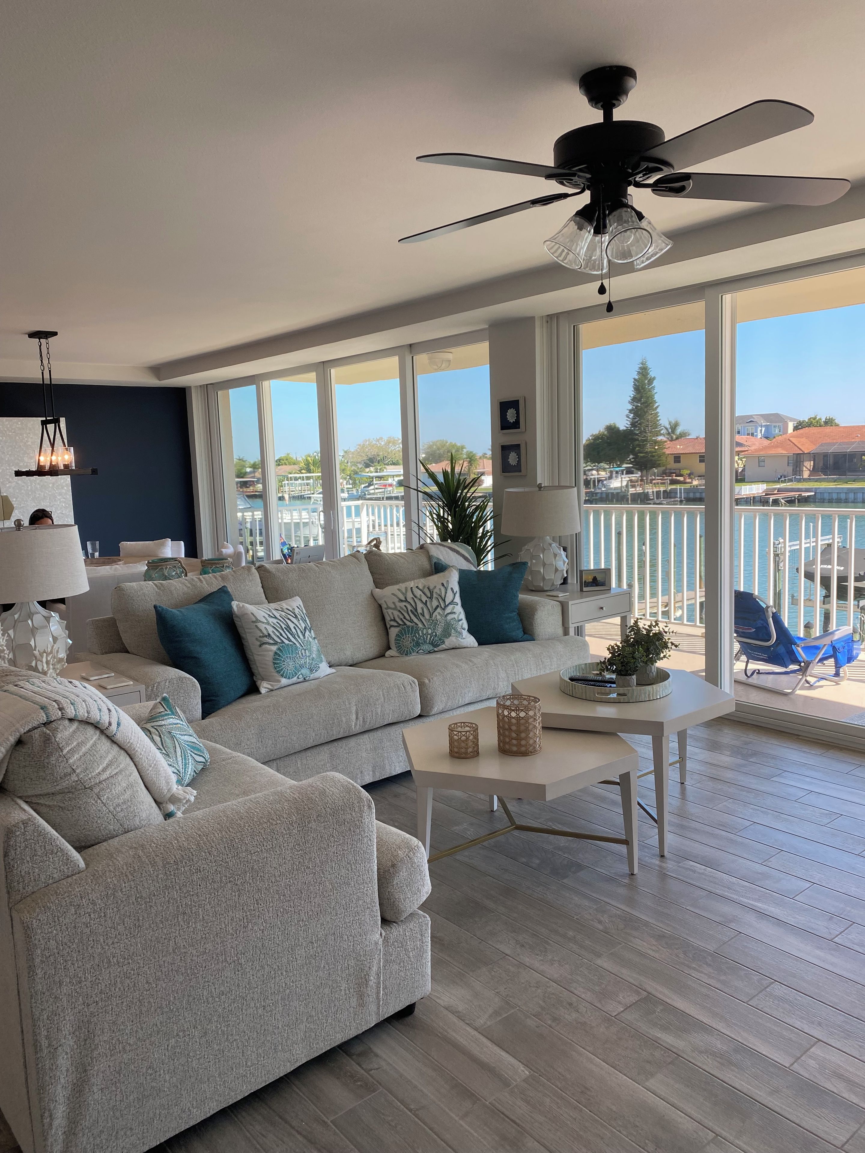 A spacious living room with a large window, a ceiling fan, and a view of the water.