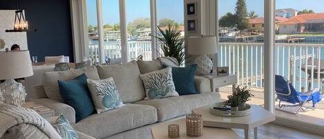 A spacious living room with a large window, a ceiling fan, and a view of the water.