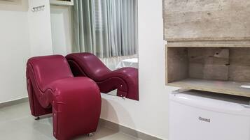 A room with two massage chairs, a small table, and a white cabinet.